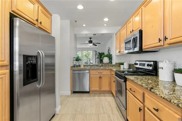 a kitchen with stainless steel appliances granite countertop a refrigerator a stove and a sink