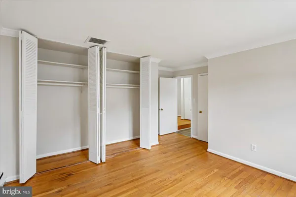 a view of an empty room with wooden floor and closet