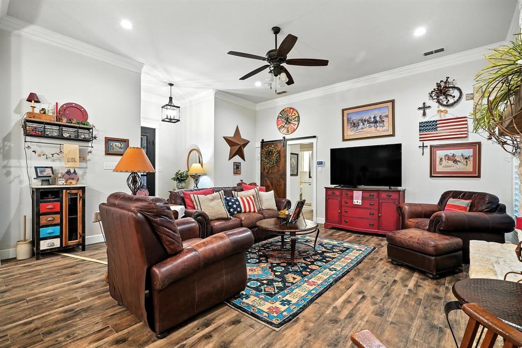136 Dove Run Tuscola, TX 79562 - Photo 11 of 37 Living room featuring crown molding, wood finished floors, a stone fireplace, ceiling fan, and recessed lighting