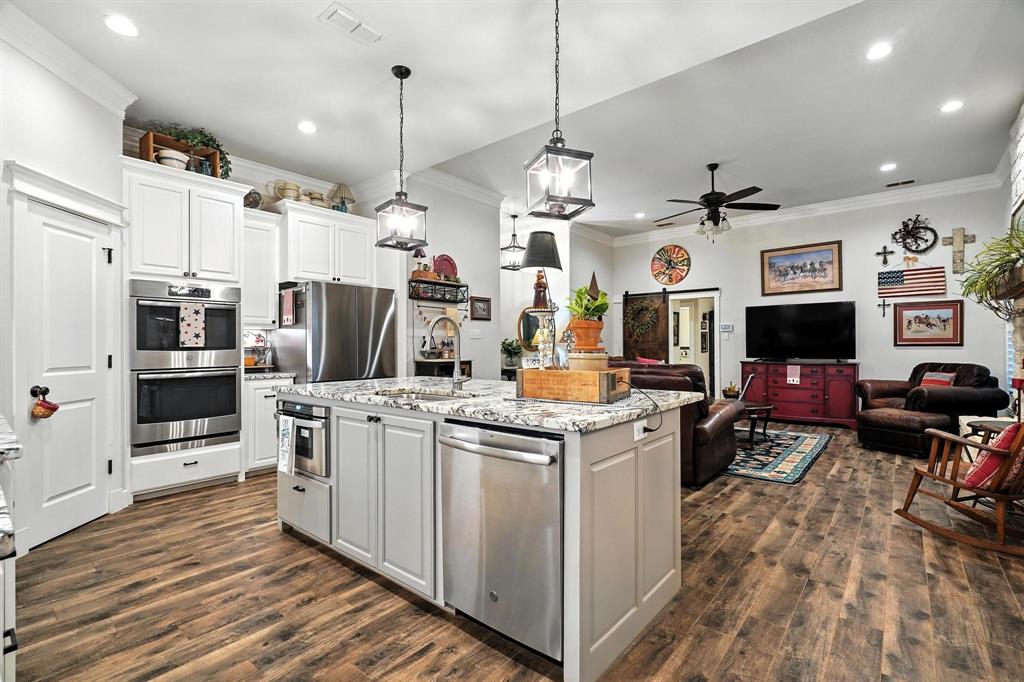 136 Dove Run Tuscola, TX 79562 - Photo 14 of 37 Kitchen featuring stainless steel appliances, decorative backsplash, crown molding, white cabinetry, dark wood-type flooring, and a kitchen island with sink