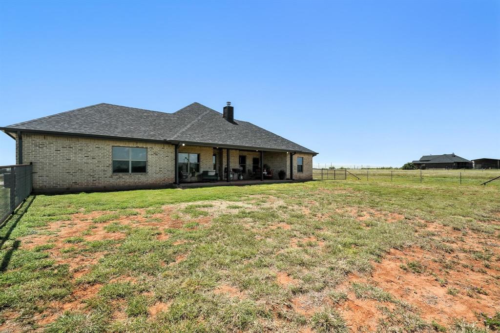 136 Dove Run Tuscola, TX 79562 - Photo 32 of 36 Rear view of house featuring fenced backyard, roof with shingles, and a chimney