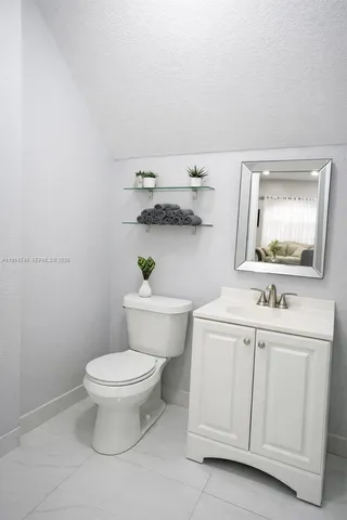 a bathroom with a white toilet sink and mirror