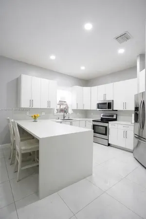 a kitchen with kitchen island granite countertop a sink and white appliances