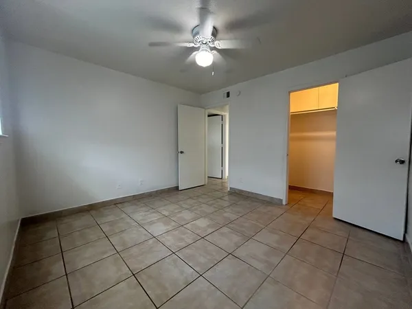 a view of an empty room and chandelier fan