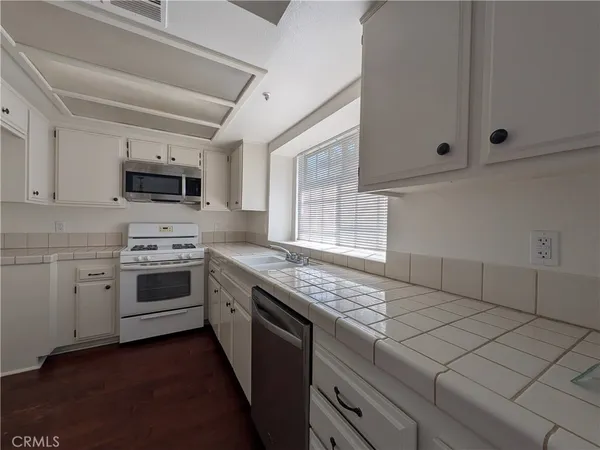 a kitchen with granite countertop a sink stainless steel appliances and cabinets