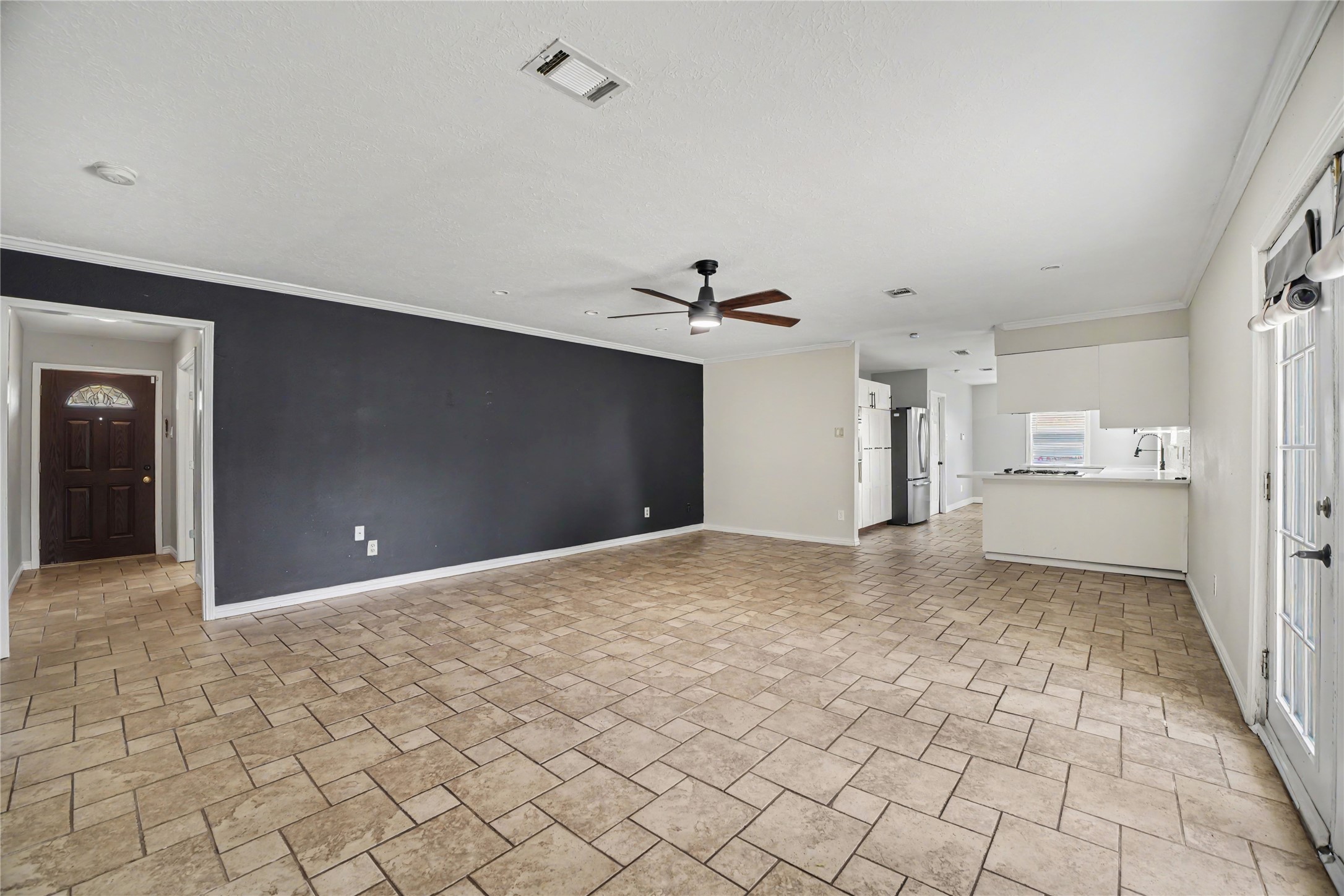 8330 Springtime Lane Houston, TX 77075 - Photo 7 of 27 Spacious open-concept living area with tile flooring, modern ceiling fan, and ample natural light from large windows.