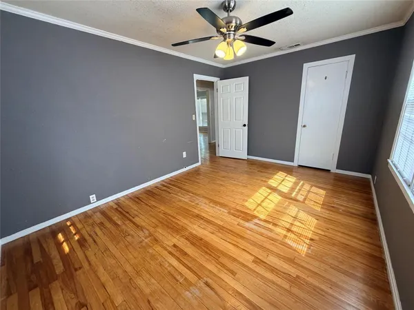 a view of empty room with wooden floor and fan