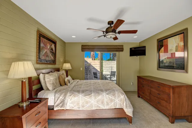 a bedroom with a large bed and a flat tv screen on dresser