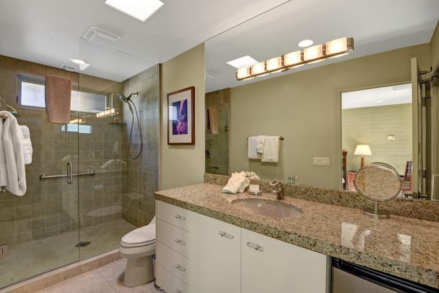 a bathroom with a granite countertop sink a toilet and shower