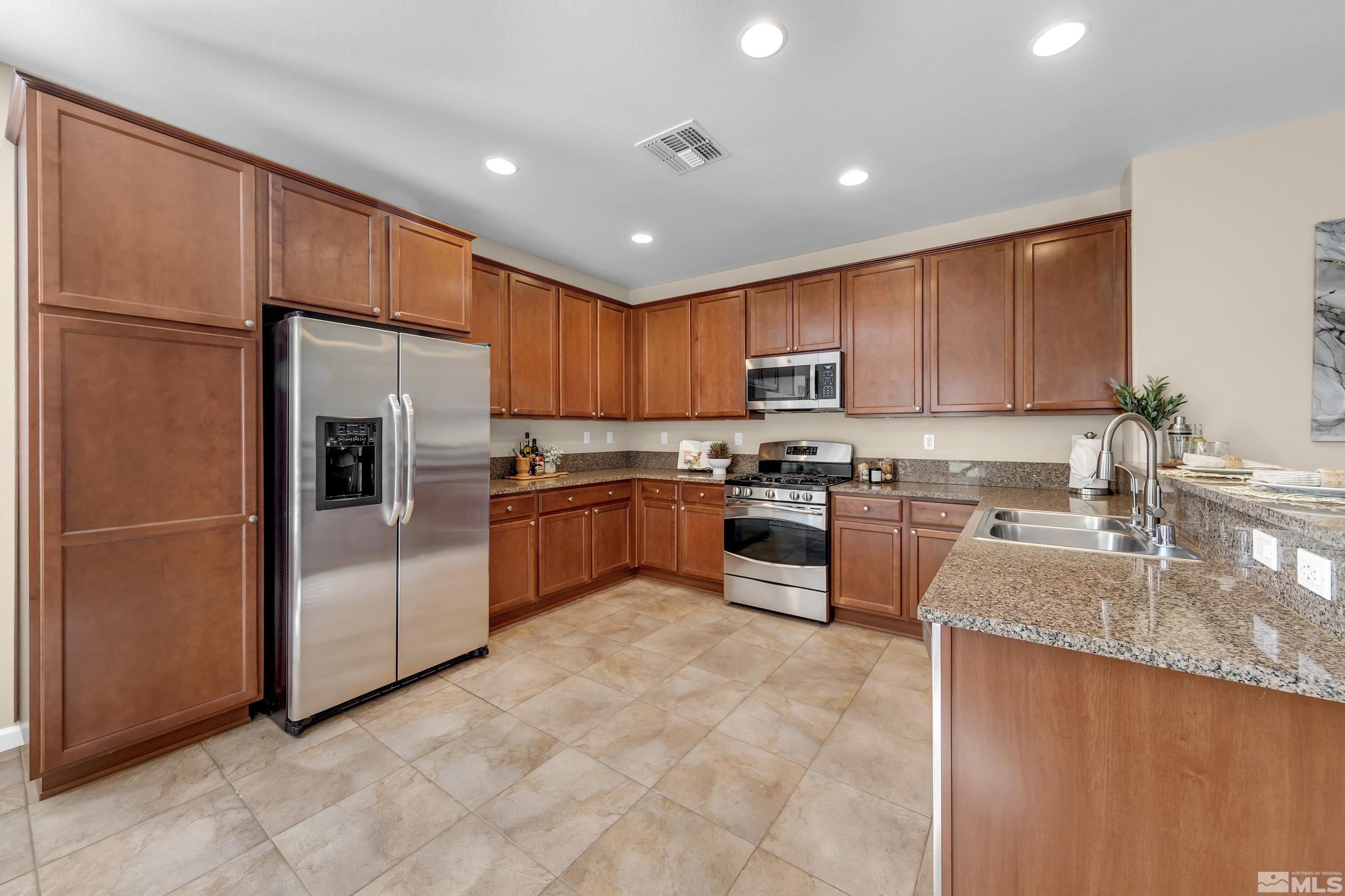 10797 Amber Falls Drive Reno, NV 89521 - Photo 26 of 38 a kitchen with granite countertop stainless steel appliances a refrigerator sink stove microwave and cabinets