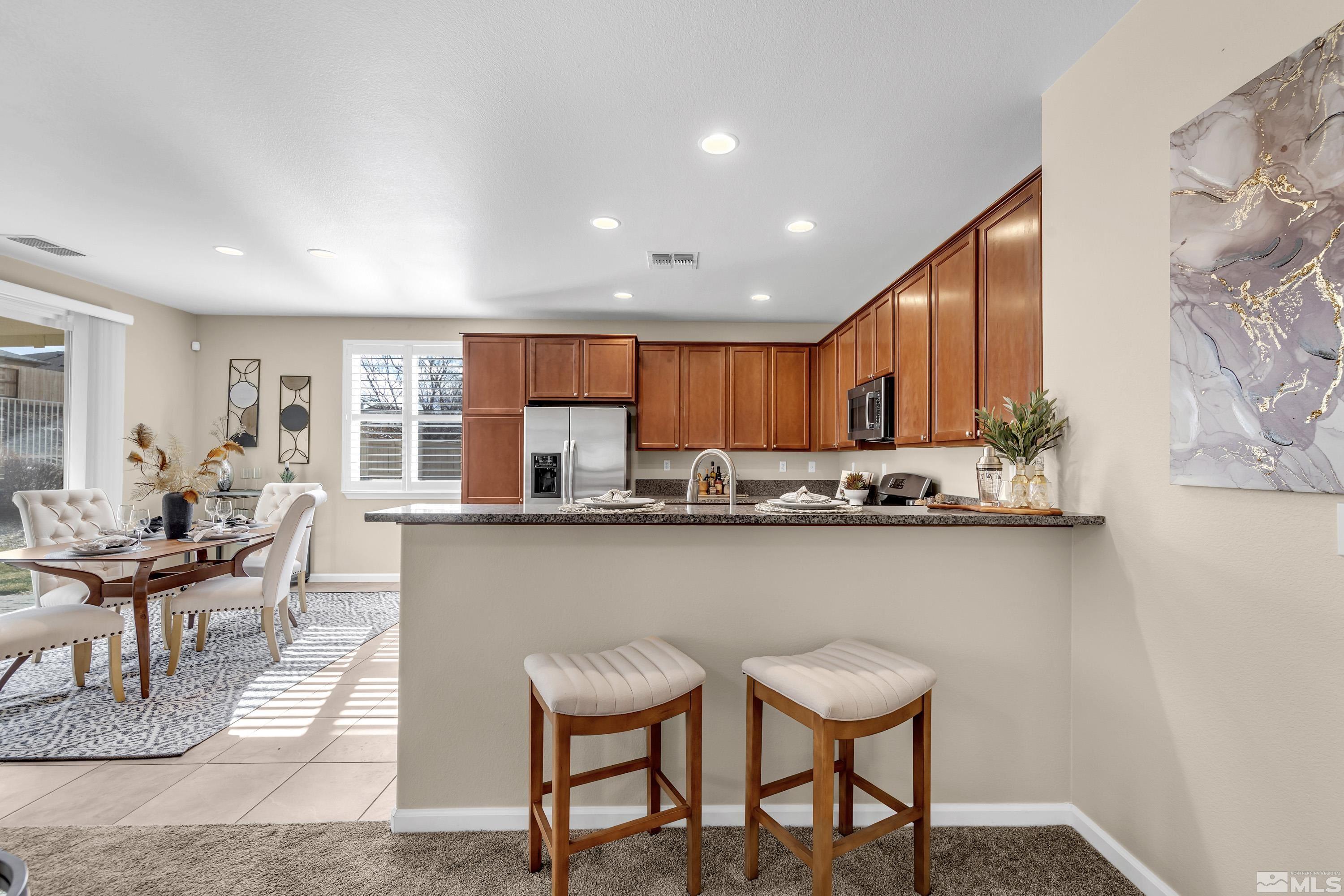10797 Amber Falls Drive Reno, NV 89521 - Photo 5 of 38 a kitchen with stainless steel appliances dining table chairs and wooden cabinets