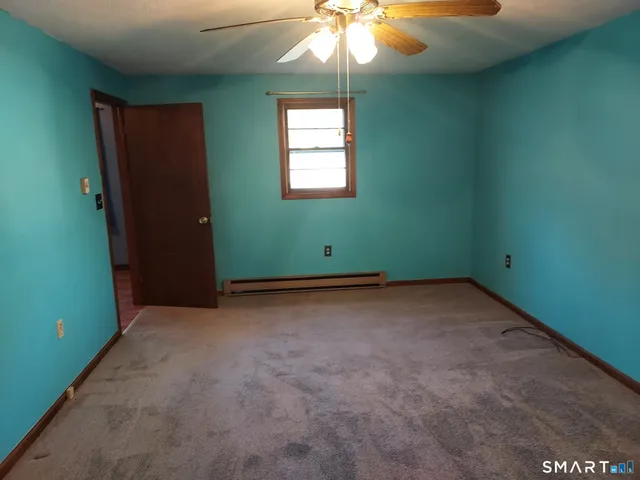 an empty room with windows and fan