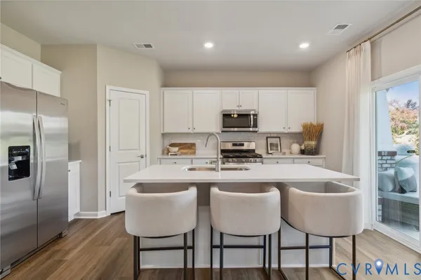 a kitchen with stainless steel appliances granite countertop a table chairs microwave and refrigerator
