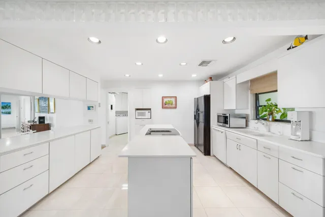 a large white kitchen with sink and lots of white cabinets