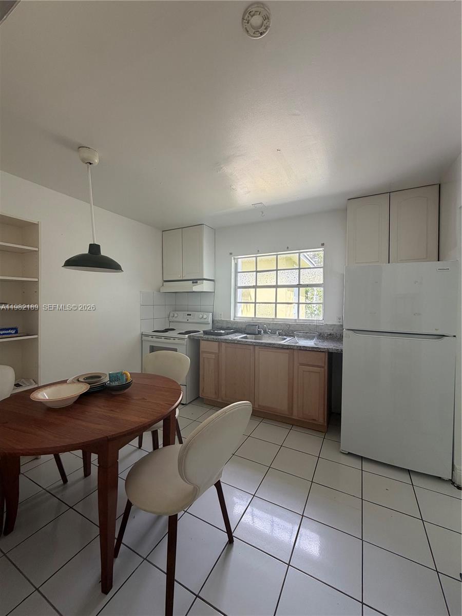 1025 Southwest 12th Street, Unit 2 Miami, FL 33129 - Photo 9 of 13 a kitchen with a table chairs and a refrigerator