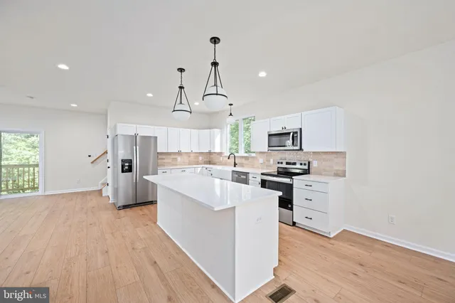 a kitchen with kitchen island granite countertop a sink a counter space appliances and cabinets
