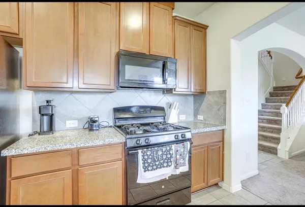 a kitchen with granite countertop a stove a sink and a microwave