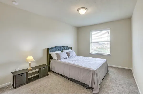 a bedroom with a bed and a lamp on the dresser