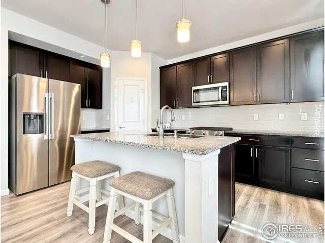 a kitchen with stainless steel appliances kitchen island granite countertop a sink refrigerator and microwave