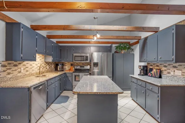 a kitchen with granite countertop a sink a counter top space appliances and cabinets