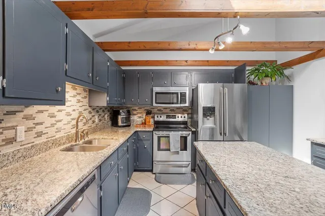 a kitchen with stainless steel appliances granite countertop a sink stove microwave and refrigerator