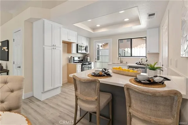 a kitchen with a sink a stove a refrigerator and white cabinets with wooden floor