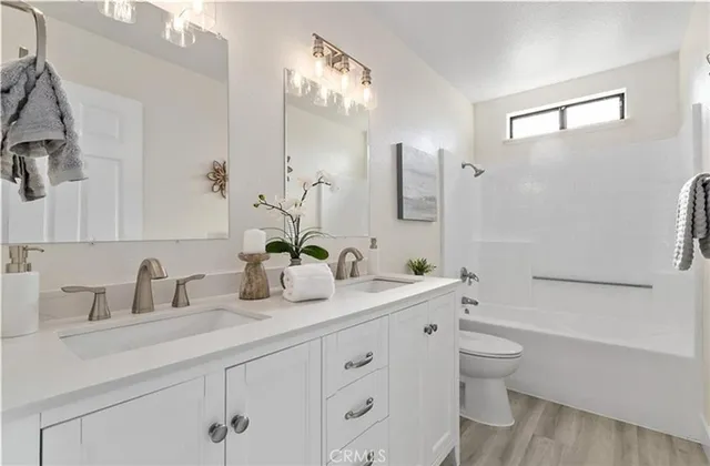 a bathroom with a double vanity sink a toilet and a bathtub