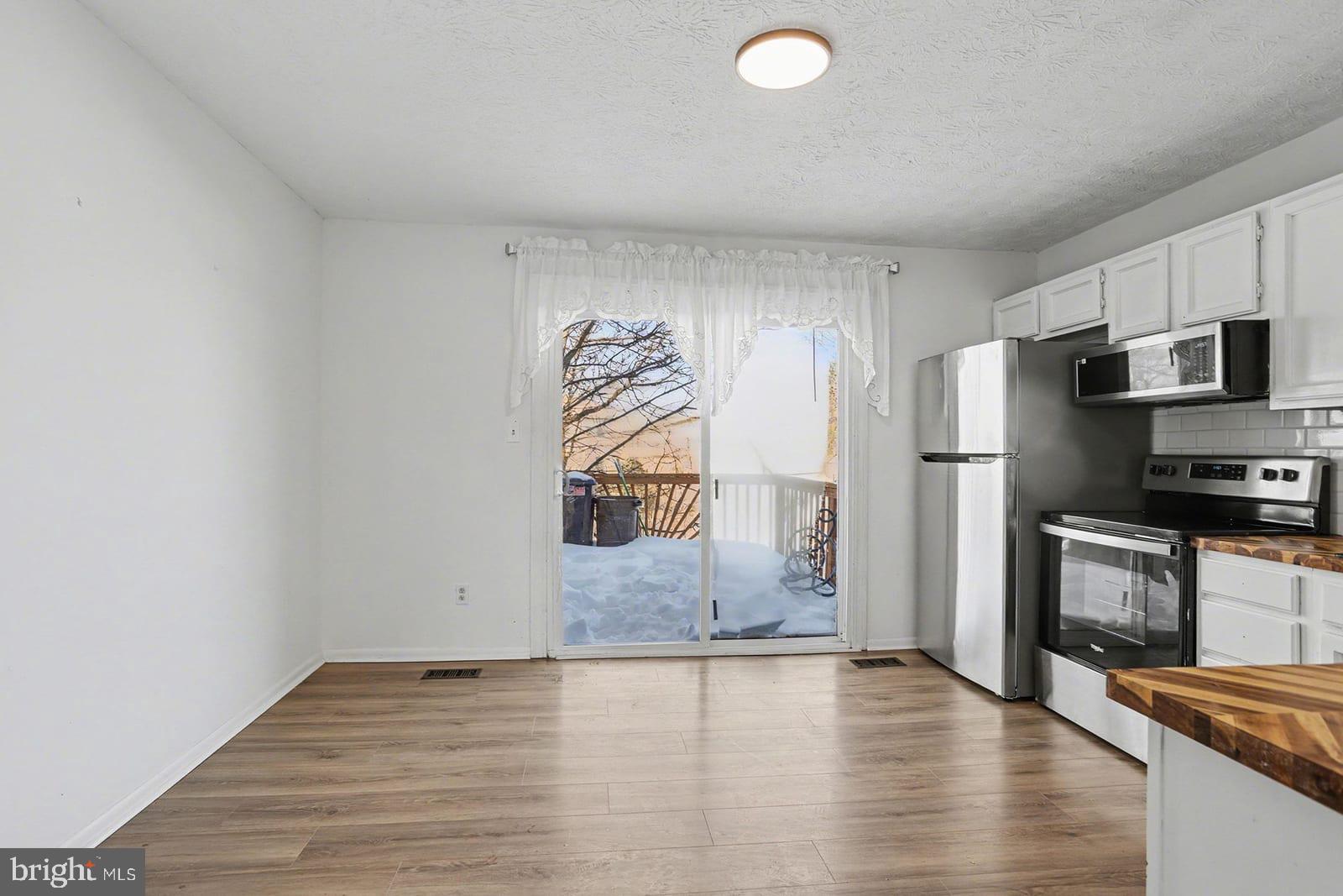 834 West Spring Meadow Court Edgewood, MD 21040 - Photo 9 of 25 a view of a refrigerator in kitchen and an empty room with wooden floor