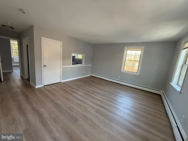 a view of an empty room with wooden floor and window