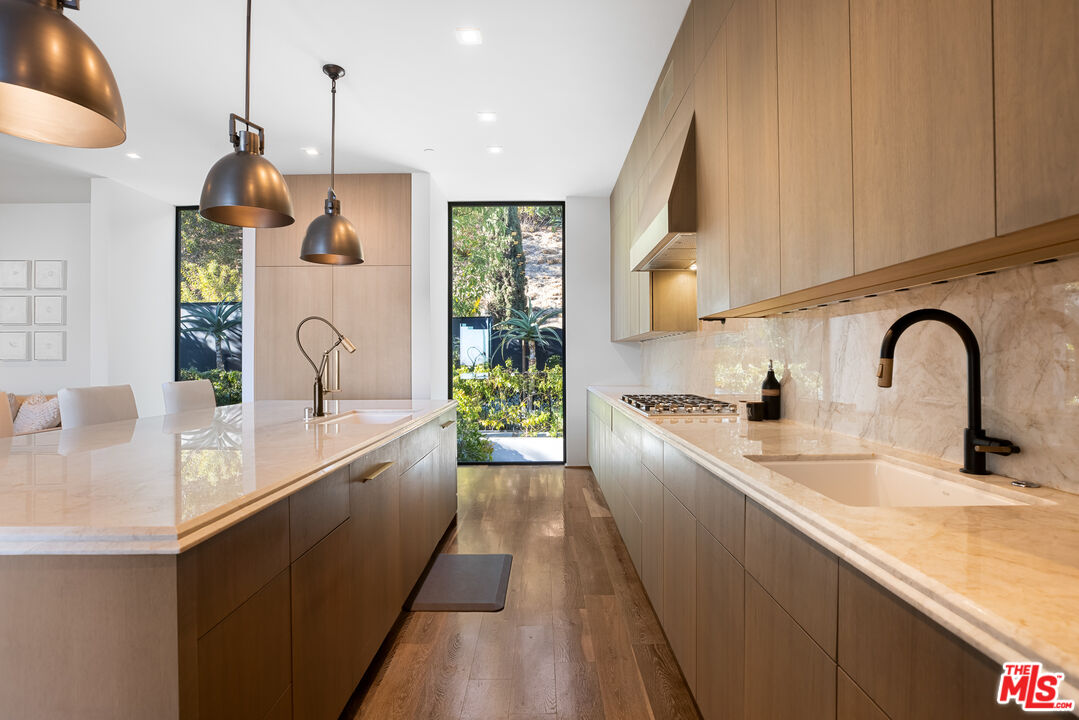 1717 Rising Glen Road Los Angeles, CA 90069 - Photo 15 of 30 a large kitchen with stainless steel appliances a sink a counter space and a window