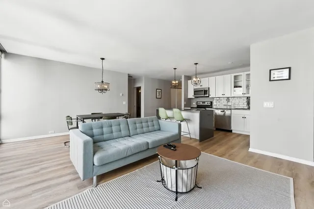 a living room with stainless steel appliances furniture and a kitchen view