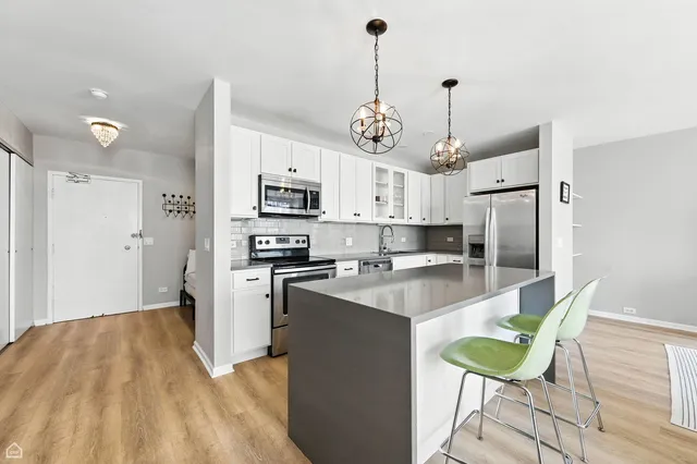 a kitchen with stainless steel appliances granite countertop a sink a stove a refrigerator cabinets and chairs