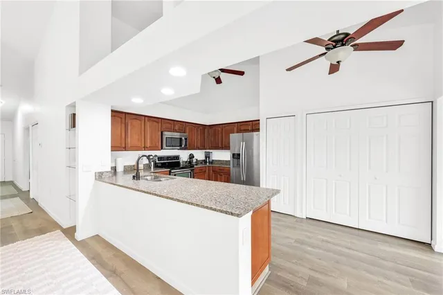 a kitchen with stainless steel appliances granite countertop a sink dishwasher a refrigerator and a cabinets with wooden floor