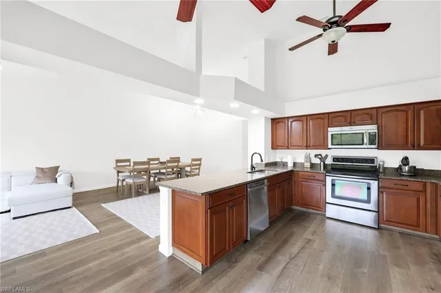 a kitchen with stainless steel appliances kitchen island hardwood floor sink stove dining table and chairs