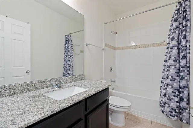 a bathroom with a granite countertop sink a toilet a mirror a vanity and shower