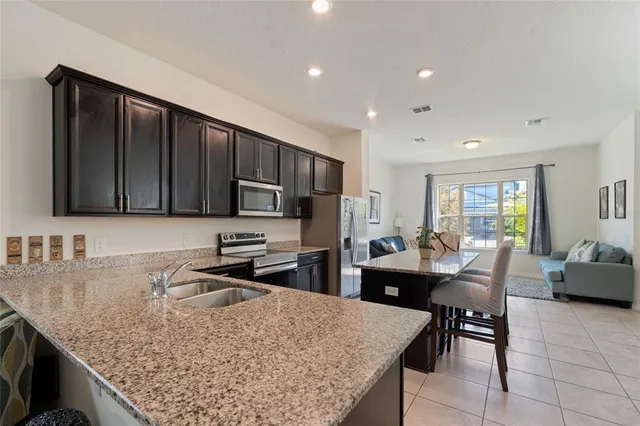 a kitchen with stainless steel appliances granite countertop a stove top oven a sink dishwasher and cabinets with wooden floor