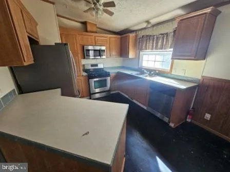 a living room with stainless steel appliances furniture a window and a kitchen view