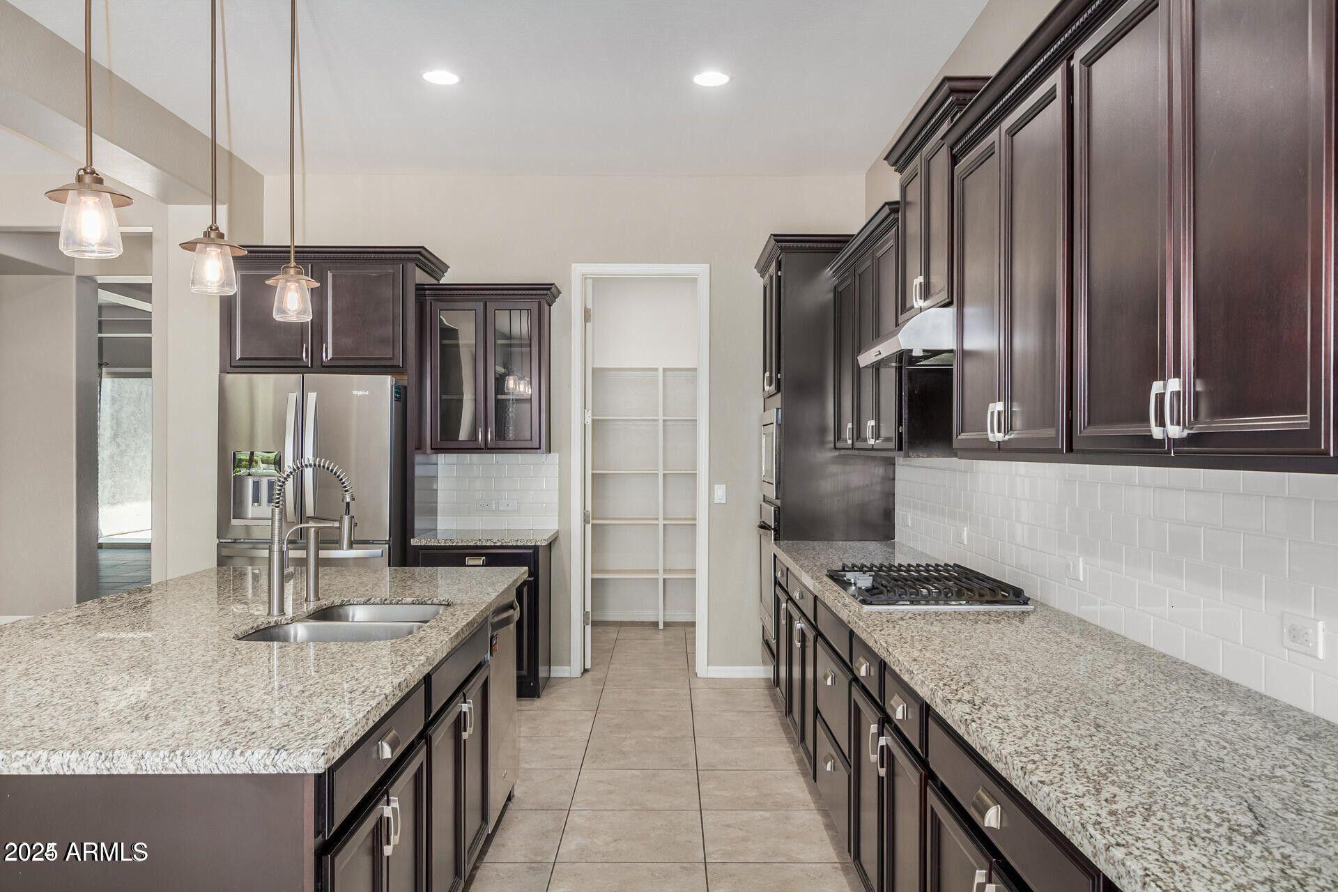 15430 South 183rd Lane Goodyear, AZ 85338 - Photo 14 of 66 a kitchen with stainless steel appliances granite countertop a sink a stove and a refrigerator