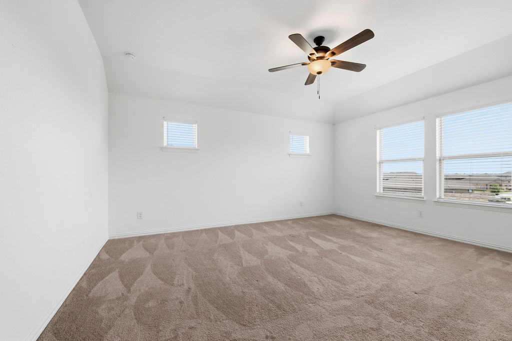 1005 Ridge Runner Drive Georgetown, TX 78628 - Photo 17 of 32 Expansive room featuring a vaulted ceiling with a ceiling fan, plush carpet flooring, and multiple windows with horizontal blinds