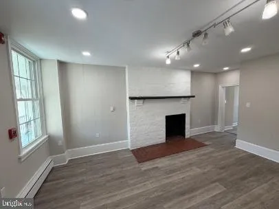 an empty room with wooden floor fireplace and windows