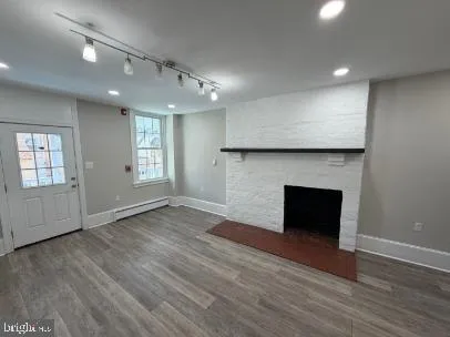 an empty room with wooden floor fireplace and windows