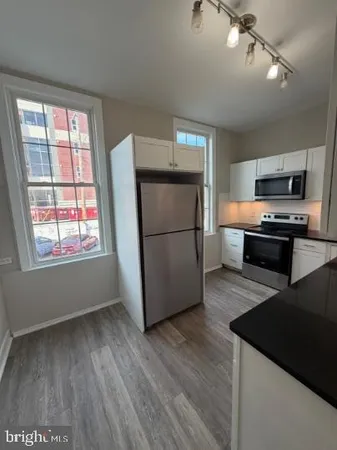 a kitchen with stainless steel appliances granite countertop a refrigerator a stove top oven a sink and dishwasher with wooden floor