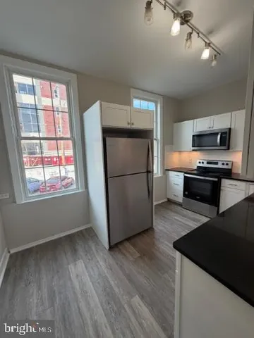 a kitchen with stainless steel appliances granite countertop a refrigerator a stove top oven a sink and dishwasher with wooden floor