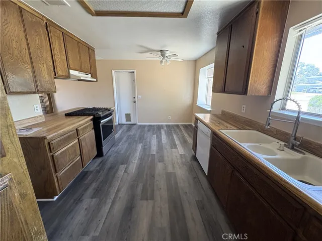 a kitchen with granite countertop wooden floors sink stove and refrigerator