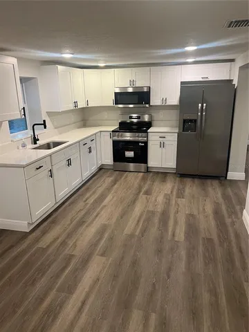 a kitchen with a sink a refrigerator and cabinets