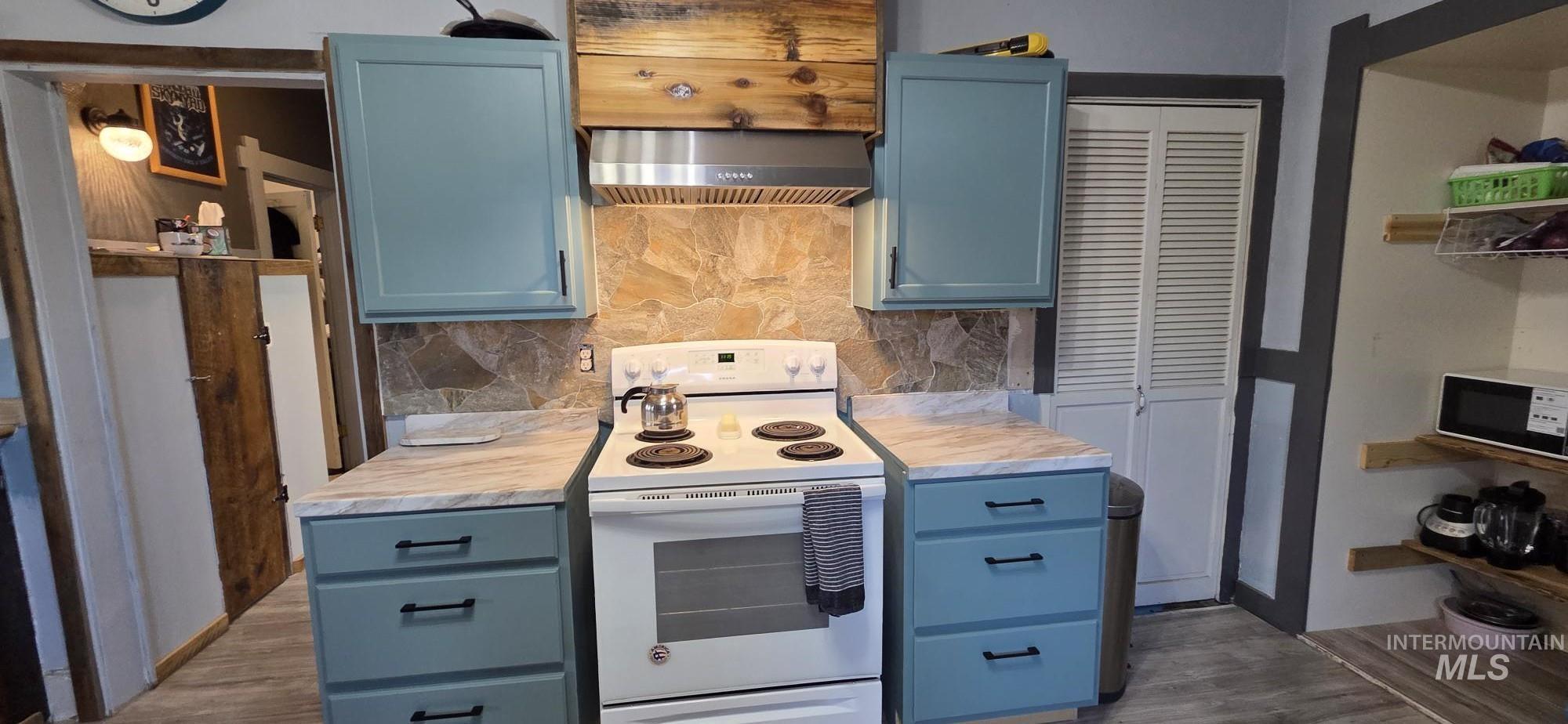 1673 Main Street Pomeroy, WA 99347 - Photo 10 of 26 Kitchen with blue cabinets, white electric range oven, light countertops, tasteful backsplash, and open shelves