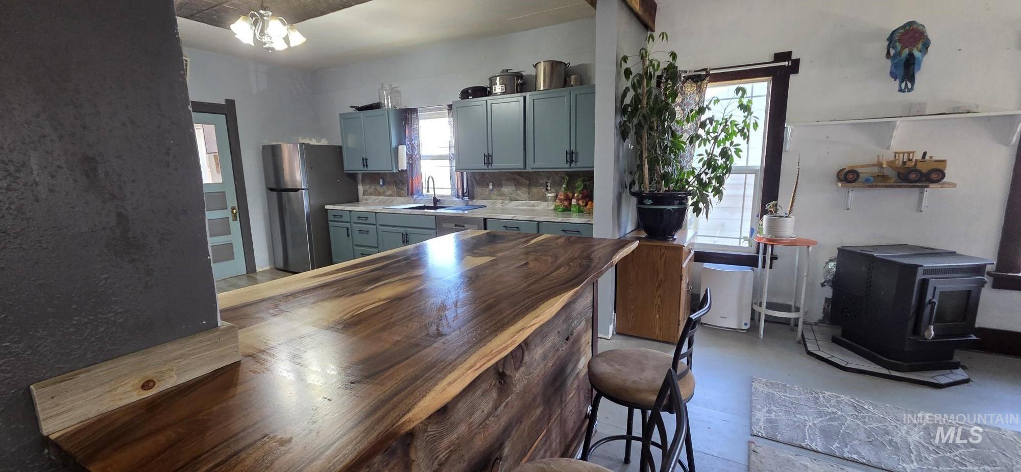 1673 Main Street Pomeroy, WA 99347 - Photo 11 of 26 Kitchen with concrete flooring, a wood stove, freestanding refrigerator, gray cabinetry, and butcher block counters