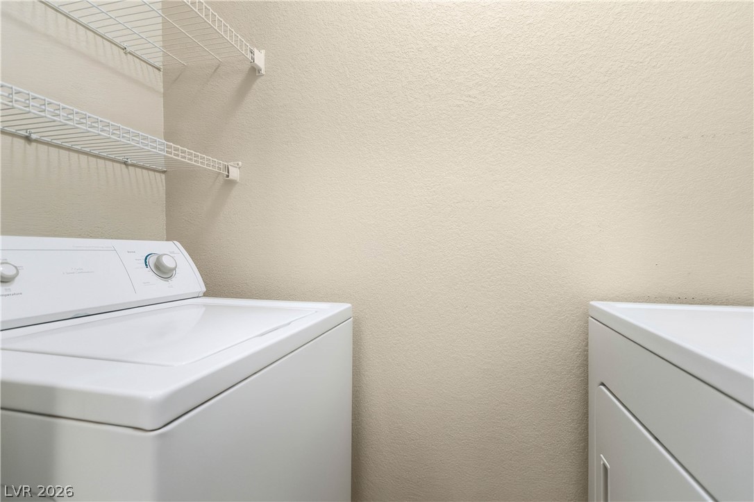 10550 West Alexander Road, Unit 2060 Las Vegas, NV 89129 - Photo 23 of 45 Functional utility space with convenient shelving above modern laundry appliances.
