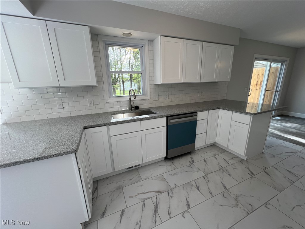 1279 Lander Road Cleveland, OH 44124 - Photo 11 of 37 Kitchen featuring stone counters, a sink, white cabinetry, dishwashing machine, and a peninsula