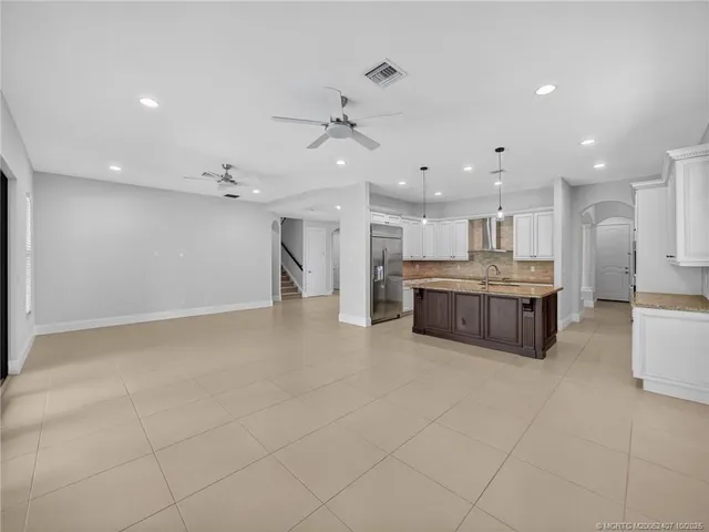 a kitchen with kitchen island granite countertop a sink and a refrigerator